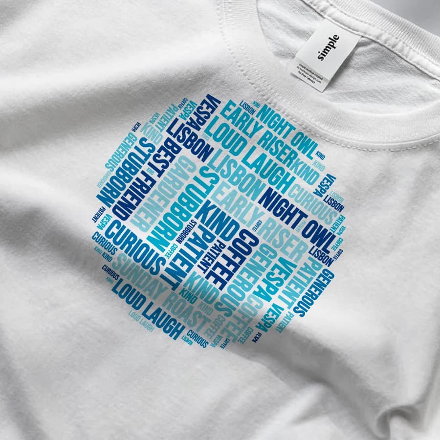 A packed word cloud of personal words in shades of blue, printed on a white tee