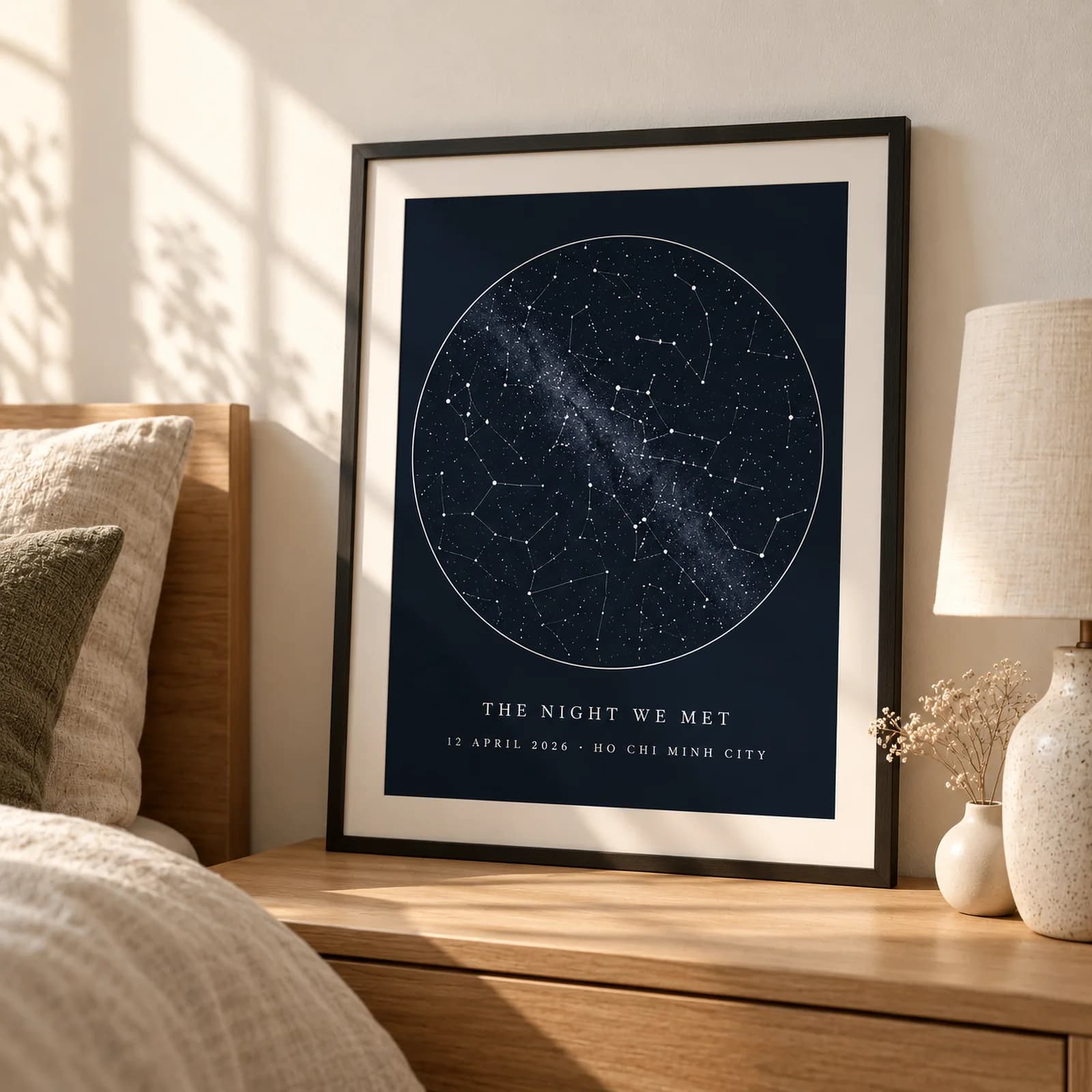 A framed navy star-map print on a bedside shelf, captioned The Night We Met, 12 April 2026, Ho Chi Minh City